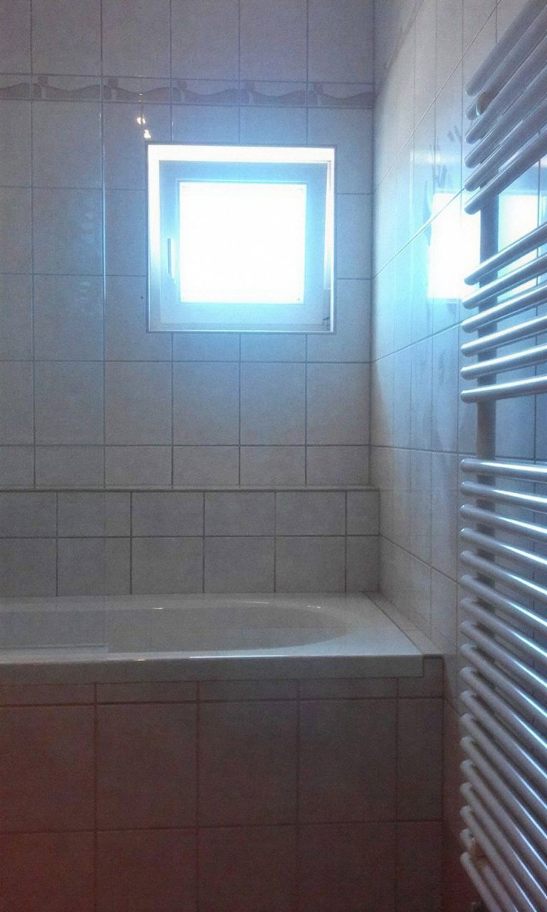Kád törölközőszárító radiátorral, csempézett fürdőszobában